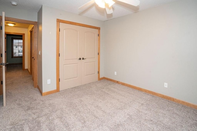 unfurnished bedroom featuring light carpet, a textured ceiling, ceiling fan, and a closet