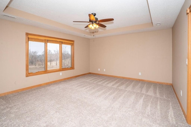 carpeted empty room featuring ceiling fan, a raised ceiling, and a textured ceiling