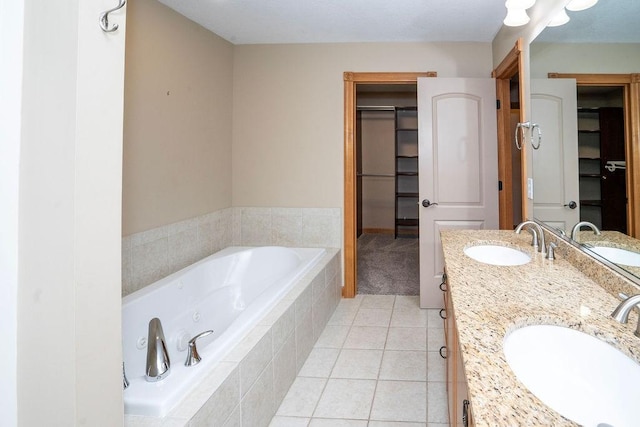 bathroom featuring tile patterned flooring, vanity, and a relaxing tiled tub