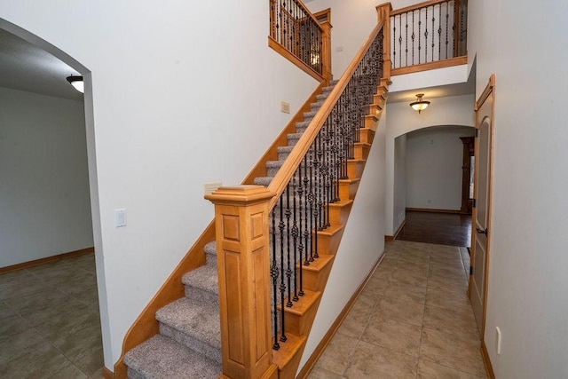 stairway featuring tile patterned floors and a high ceiling