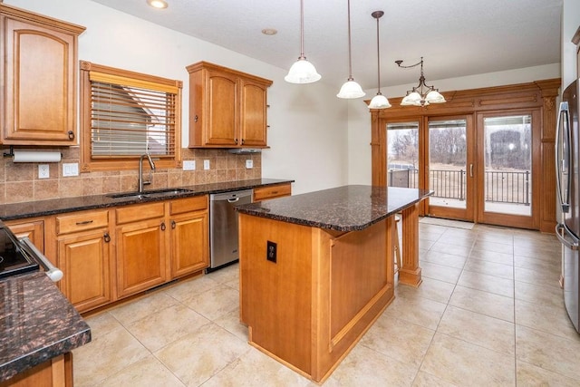 kitchen featuring a kitchen island, appliances with stainless steel finishes, decorative light fixtures, sink, and decorative backsplash