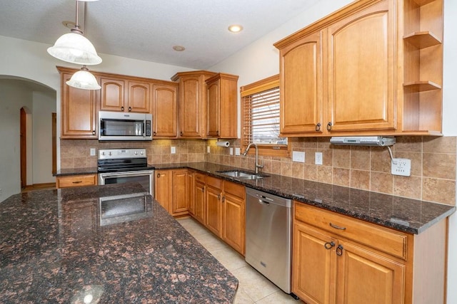 kitchen featuring decorative light fixtures, tasteful backsplash, sink, dark stone countertops, and stainless steel appliances