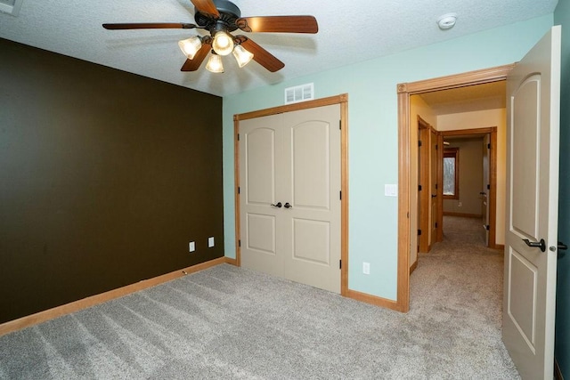 unfurnished bedroom with ceiling fan, light carpet, and a textured ceiling