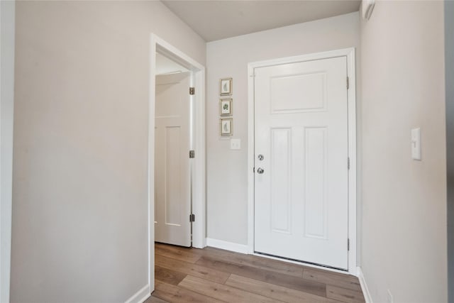 doorway with light wood-type flooring and baseboards