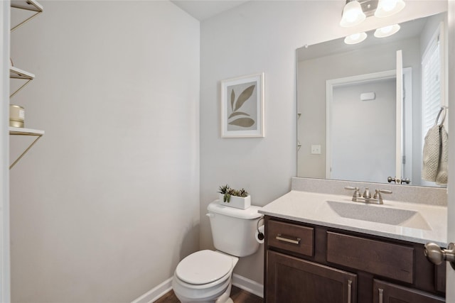 half bathroom featuring toilet, baseboards, and vanity