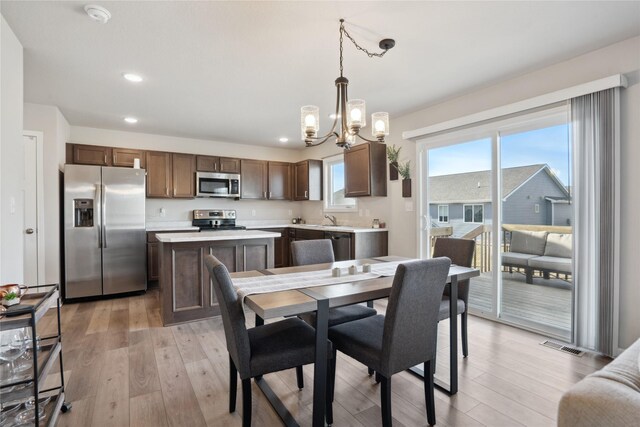 dining area with sink, light hardwood / wood-style floors, and a notable chandelier