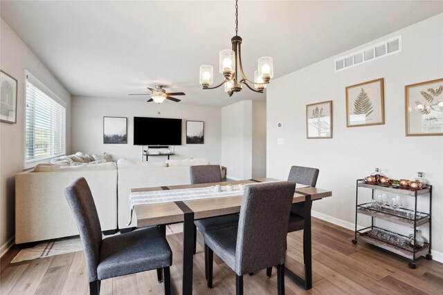 dining area featuring hardwood / wood-style flooring and ceiling fan with notable chandelier