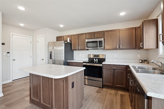 kitchen with sink, a kitchen island, light hardwood / wood-style floors, and appliances with stainless steel finishes