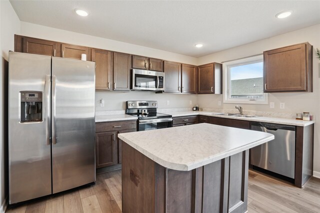 kitchen with sink, light hardwood / wood-style flooring, dark brown cabinets, stainless steel appliances, and a kitchen island