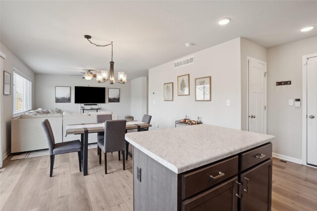 kitchen with a kitchen island, a chandelier, hanging light fixtures, light hardwood / wood-style floors, and dark brown cabinets