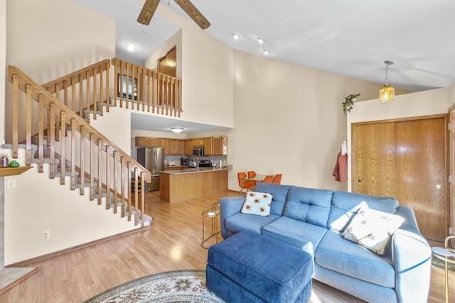 living room featuring ceiling fan, high vaulted ceiling, and light hardwood / wood-style floors