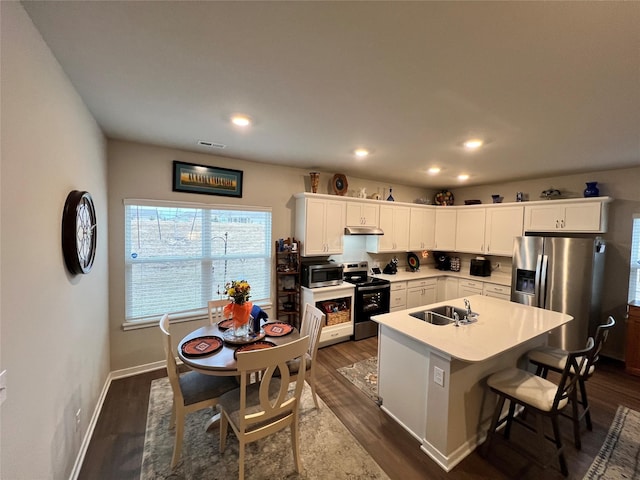 kitchen featuring dark wood-type flooring, sink, appliances with stainless steel finishes, a kitchen island, and white cabinets