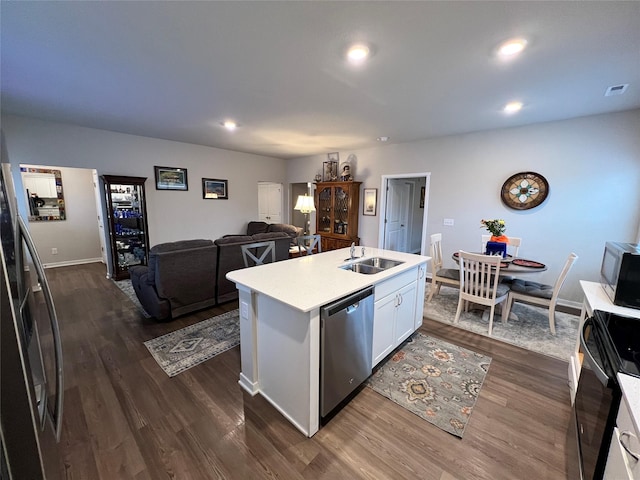 kitchen with appliances with stainless steel finishes, an island with sink, sink, white cabinets, and dark hardwood / wood-style flooring