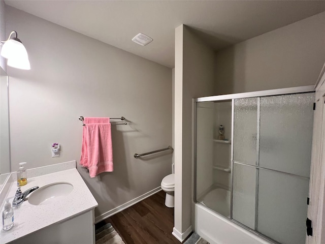 full bathroom featuring vanity, hardwood / wood-style flooring, bath / shower combo with glass door, and toilet