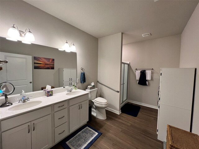 bathroom with wood-type flooring, toilet, an enclosed shower, and vanity