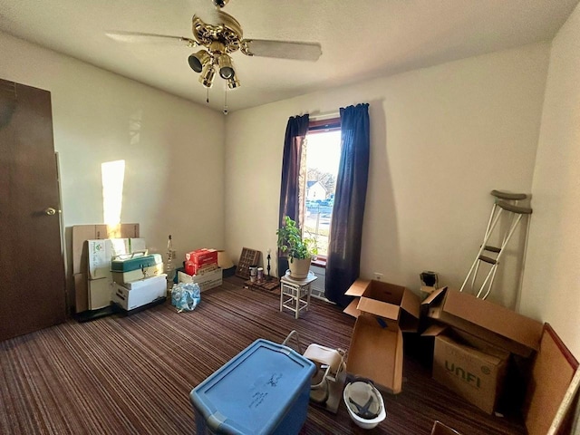 interior space with ceiling fan and dark colored carpet