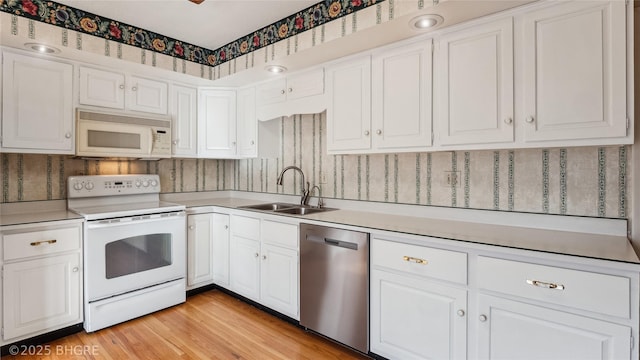 kitchen featuring light wood-type flooring, white appliances, sink, and white cabinets