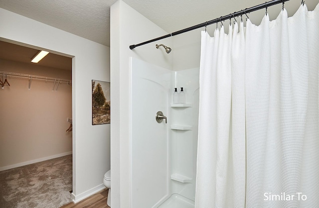 bathroom featuring toilet, a textured ceiling, and a shower with shower curtain