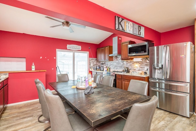 dining space with ceiling fan, vaulted ceiling, and light hardwood / wood-style flooring