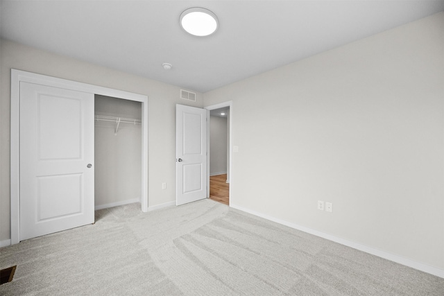 unfurnished bedroom featuring light carpet and a closet