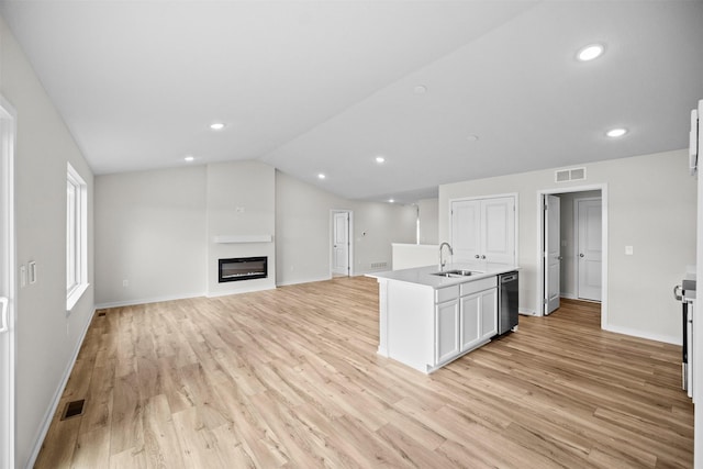 kitchen with sink, light hardwood / wood-style flooring, a kitchen island with sink, white cabinets, and vaulted ceiling