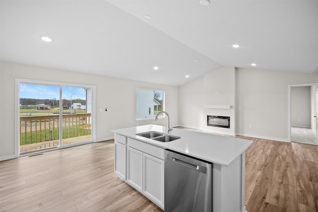 kitchen with lofted ceiling, sink, dishwasher, an island with sink, and white cabinets