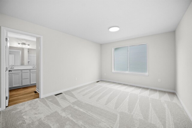 interior space featuring connected bathroom, sink, and light carpet