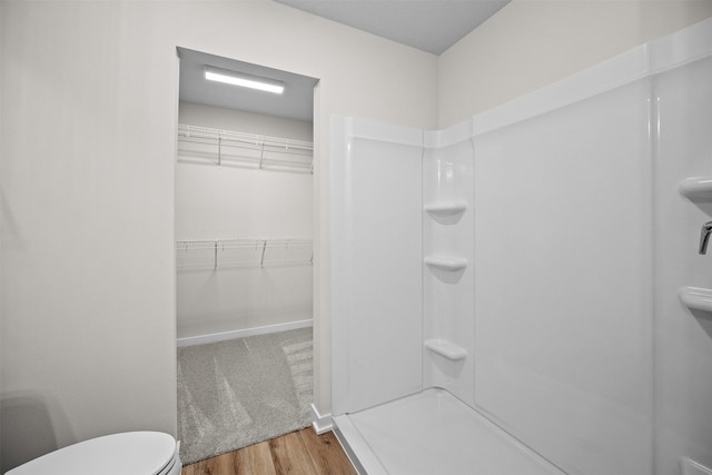 bathroom with walk in shower, toilet, and hardwood / wood-style floors