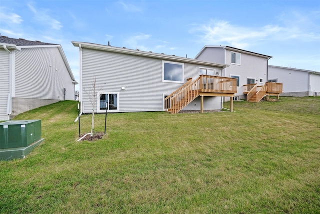 rear view of house featuring a wooden deck and a lawn