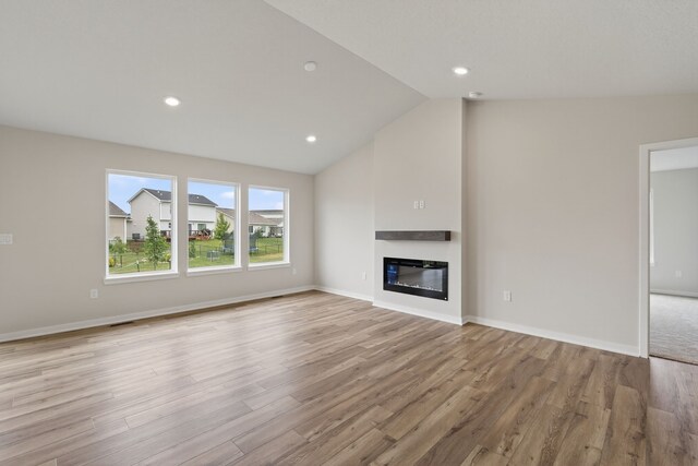 1835 Tuscany Dr SE, Altoona, IA 50009 - unfurnished living room featuring light wood-style flooring, a glass covered fireplace, lofted ceiling, and recessed lighting