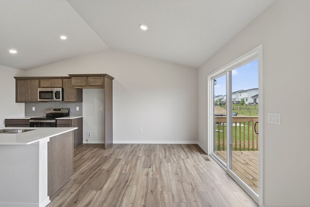 1835 Tuscany Dr SE, Altoona, IA 50009 - kitchen featuring appliances with stainless steel finishes, lofted ceiling, light wood-style floors, decorative backsplash, and light countertops