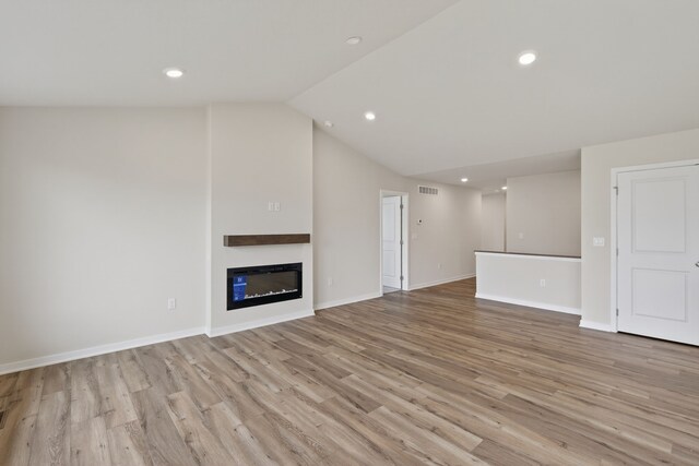 1835 Tuscany Dr SE, Altoona, IA 50009 - unfurnished living room with light wood finished floors, lofted ceiling, a glass covered fireplace, and recessed lighting