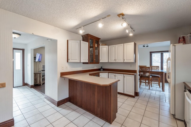 kitchen featuring white cabinetry, kitchen peninsula, light tile patterned flooring, and white fridge