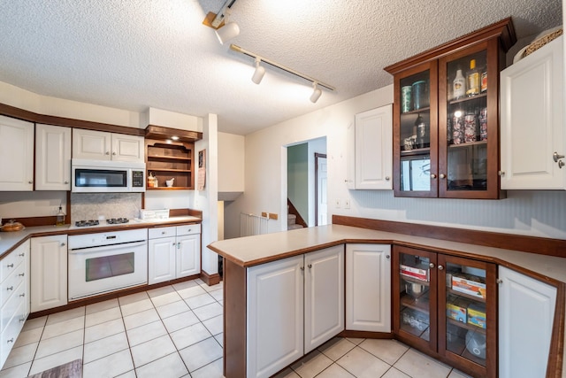 kitchen with white cabinets, light tile patterned floors, white appliances, kitchen peninsula, and a textured ceiling