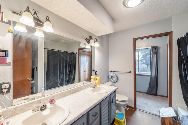 bathroom with hardwood / wood-style flooring, vanity, a textured ceiling, and toilet