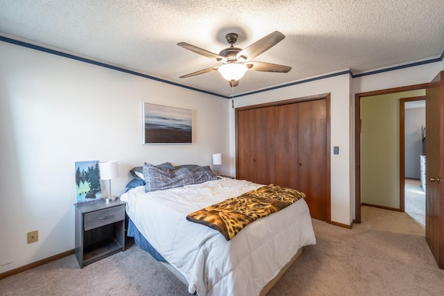 bedroom featuring ceiling fan, ornamental molding, a textured ceiling, light colored carpet, and a closet