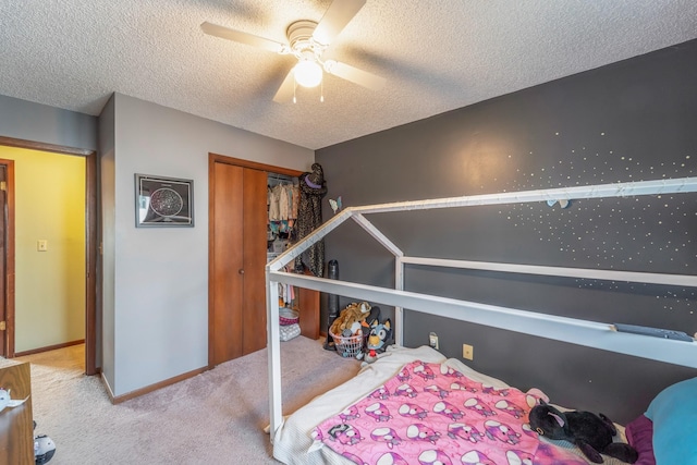 bedroom featuring light carpet, ceiling fan, a closet, and a textured ceiling