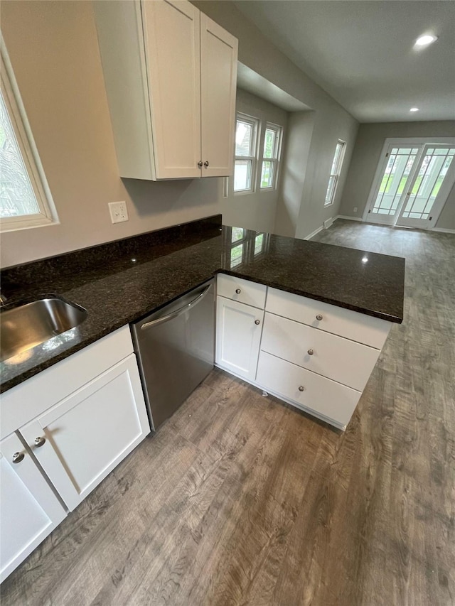 kitchen featuring dark stone counters, dishwasher, hardwood / wood-style floors, and white cabinets