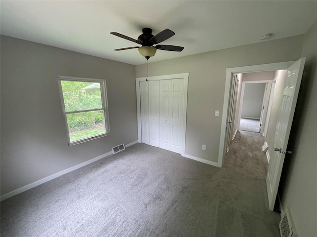 unfurnished bedroom with dark colored carpet, ceiling fan, and a closet