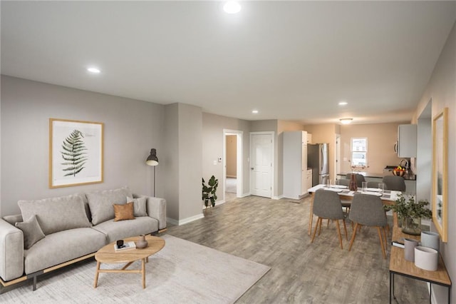 living room with recessed lighting, baseboards, and light wood-type flooring