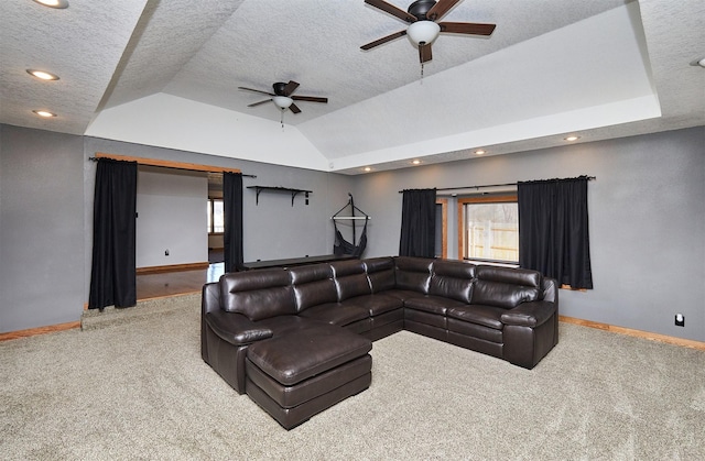 carpeted living room featuring ceiling fan, lofted ceiling, a textured ceiling, and a tray ceiling