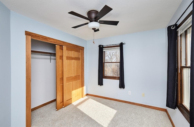 unfurnished bedroom with light carpet, ceiling fan, a closet, and a textured ceiling