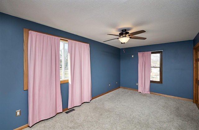 spare room featuring ceiling fan, light carpet, and a textured ceiling