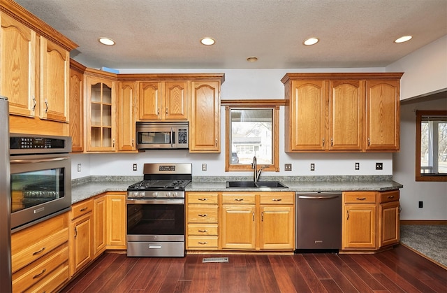 kitchen featuring appliances with stainless steel finishes, dark hardwood / wood-style floors, sink, and a textured ceiling