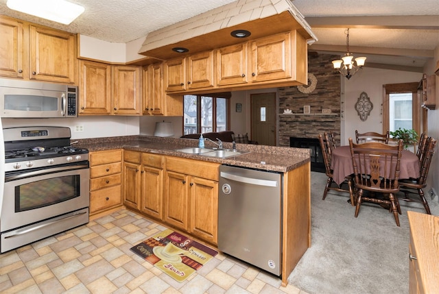 kitchen featuring appliances with stainless steel finishes, pendant lighting, sink, kitchen peninsula, and a textured ceiling