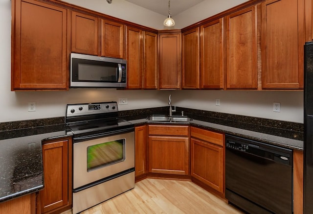 kitchen with sink, hanging light fixtures, light hardwood / wood-style flooring, dark stone countertops, and stainless steel appliances