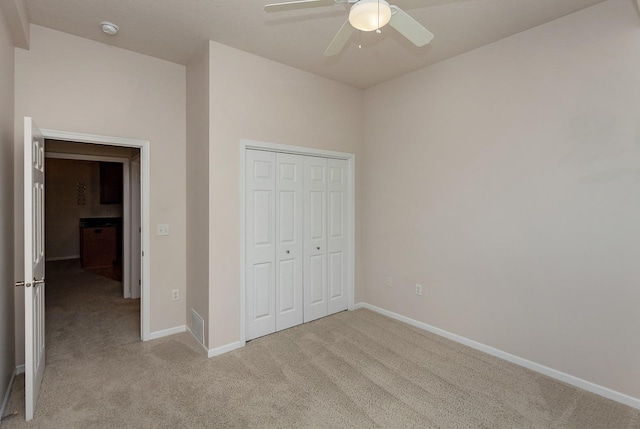 unfurnished bedroom with ceiling fan, a closet, and light carpet