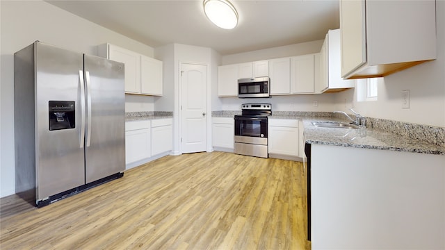 kitchen featuring sink, light hardwood / wood-style flooring, stainless steel appliances, light stone counters, and white cabinets