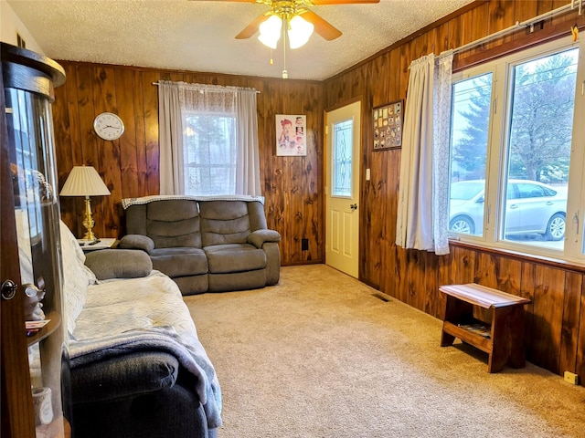 living room featuring light carpet, a textured ceiling, and wooden walls