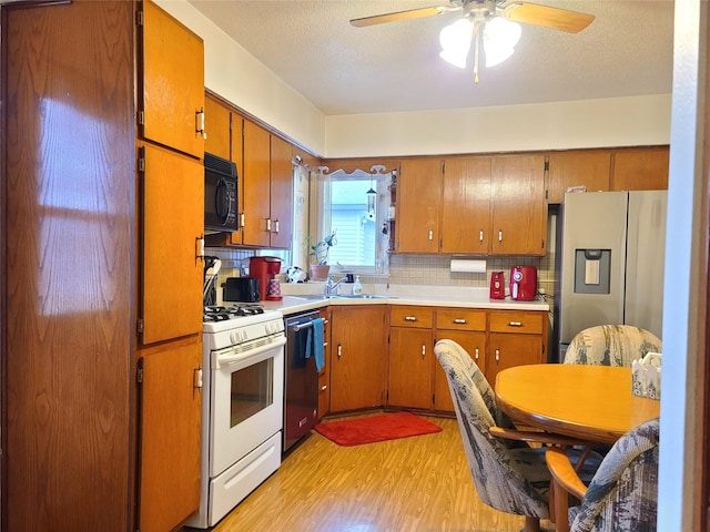 kitchen featuring sink, stainless steel appliances, light hardwood / wood-style floors, a textured ceiling, and decorative backsplash